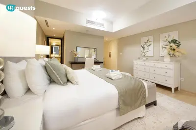 a bedroom with a large white bed and a dresser at HiGuests - Fabulous Duplex With Breathtaking Lake Views in Dubai