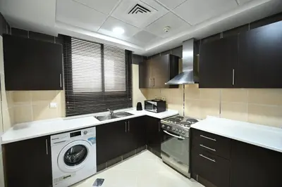 a kitchen with black cabinets and a washer and dryer at Al Waleed Holiday Homes in Dubai