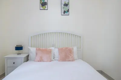 a bedroom with a white bed with pink pillows at Charming 3 BR with walking distance to the Beach in Dubai