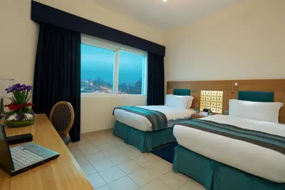 a hotel room with two beds and a desk with a laptop at Tamani Marina Hotel & Apartments in Dubai