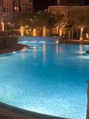 a large swimming pool with blue water at night at Balqis Residense Palm Jumeirah,Pool, Beach, Top floor, Full sea view, Restaurants in Dubai