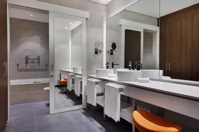 a bathroom with three sinks and a toilet at Aloft Al Mina, Dubai Jumeirah in Dubai