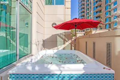 a hot tub on a balcony with an umbrella at bnbme - Dubai Marina 2BR Apt w Private Jacuzzi Pool Gym Near JBR Beach & Marina Walk in Dubai