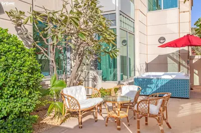 a patio with chairs and a glass table and umbrella at bnbme - Dubai Marina 2BR Apt w Private Jacuzzi Pool Gym Near JBR Beach & Marina Walk in Dubai