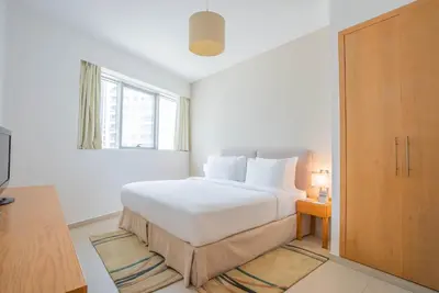 a white bedroom with a white bed and a window at Grand Heights Dubai Hotel Apartments in Dubai