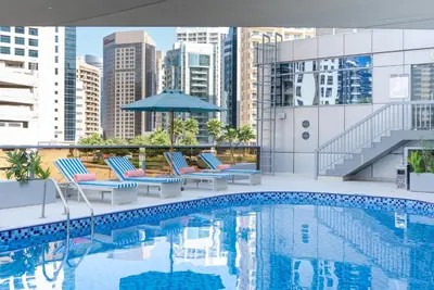 a pool with chairs and an umbrella on top of a building at Grand Heights Dubai Hotel Apartments in Dubai