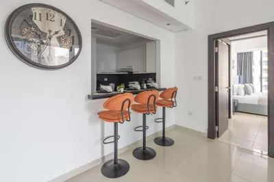 a kitchen with three bar stools and a mirror at Frank Porter - Silverene in Dubai