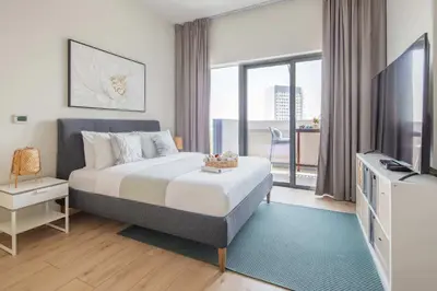 a bedroom with a bed and a tv and a balcony at Frank Porter - Azizi Aura in Dubai