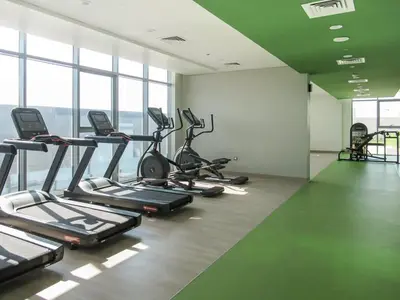 a gym with several tread machines in a room with windows at Frank Porter - Azizi Aura in Dubai