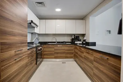 a large kitchen with wooden cabinets and a sink at 1BD apt in Sparkle Tower by Swarovsky big capacity in Dubai