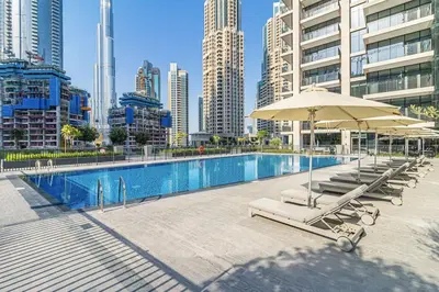 a pool with lounge chairs and umbrellas in a city at Elegant Apt With Balcony Minutes from Burj Khalifa in Dubai