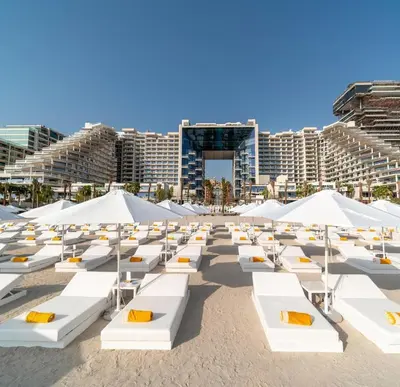 a beach with white lounge chairs and umbrellas at FIVE Palm Residence - Platinium Dubai in Dubai