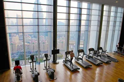 a gym with rows of exercise bikes in front of a large window at Index Tower by Radiance Vacation Stays 43rd Floor in Dubai