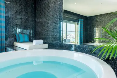 a bath tub in a bathroom with black tiles at The Westin Dubai Mina Seyahi Beach Resort and Waterpark in Dubai