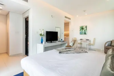 a white room with a bed and a tv at The Smart Concierge - The Vogue in Dubai