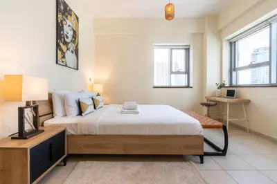 a bedroom with a bed and a table and windows at Scenic 2 Bedroom Apartment - Downtown Business Bay in Dubai