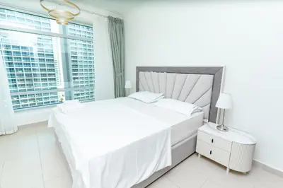 a white bedroom with a large bed and a window at Holidays R Us canal view in Dubai