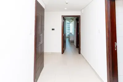 a hallway with white tile floors and wooden doors at Holidays R Us canal view in Dubai