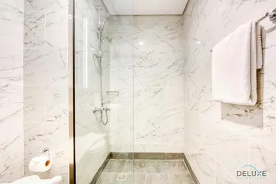 a bathroom with a shower with white marble walls at Snug 1BR at MAG 520 Dubai South by Deluxe Holiday Homes in Dubai