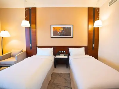 a hotel room with two beds and a chair at Asma Hotel Al Barsha in Dubai