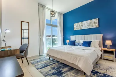 a blue bedroom with a bed and a chair at Live Modern Live Luxury - Dubai Studio City in Dubai