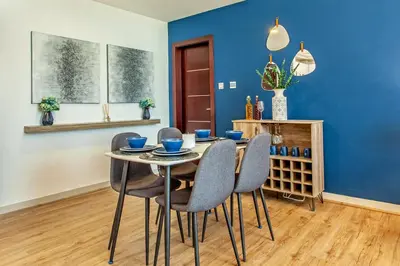 a dining room with blue walls and a table and chairs at Live Modern Live Luxury - Dubai Studio City in Dubai