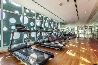 a gym with a row of treadmills in a room at Live Modern Live Luxury - Dubai Studio City in Dubai