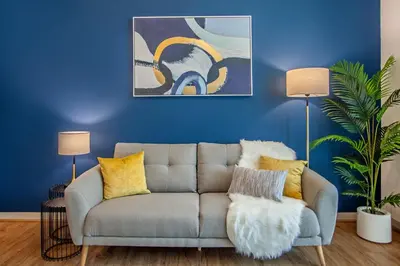 a living room with a couch and a blue wall at Live Modern Live Luxury - Dubai Studio City in Dubai