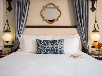 a bedroom with a white bed with a blue pillow and a mirror at Jumeirah Al Qasr Dubai in Dubai