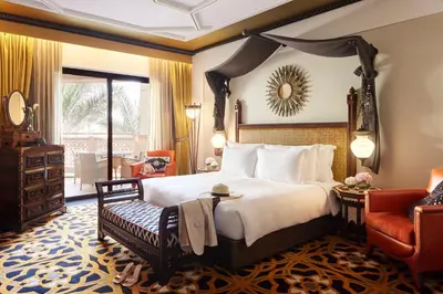 a bedroom with a king sized bed and a chair at Jumeirah Al Qasr Dubai in Dubai