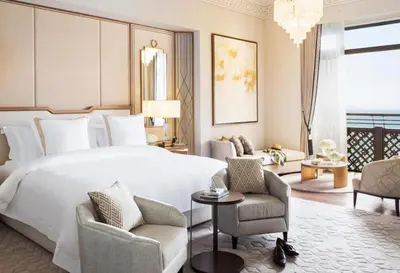 a bedroom with a large white bed and two chairs at Jumeirah Mina Al Salam Dubai in Dubai