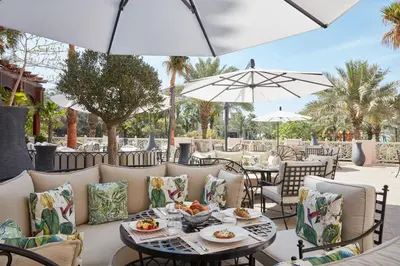 an outdoor patio with tables and chairs and umbrellas at Jumeirah Dar Al Masyaf Dubai in Dubai