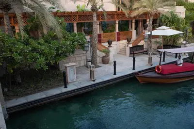 a boat in the water in front of a house at Jumeirah Dar Al Masyaf Dubai in Dubai