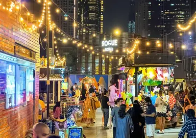 a crowd of people walking on a city street at night at Ramada Hotel, Suites and Apartments by Wyndham Dubai JBR in Dubai