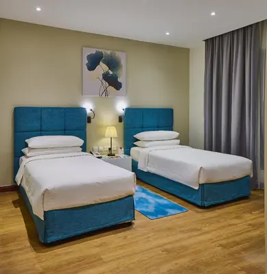 a bedroom with two beds with blue headboards at Ramada Hotel, Suites and Apartments by Wyndham Dubai JBR in Dubai