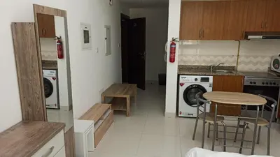 a kitchen with a table and a washing machine at Furnished Studio Apartments for rent in Dubai in Dubai