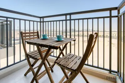 a wooden table and two chairs on a balcony at Spotless 1BR at UNA Town Square Dubailand by Deluxe Holiday Homes in Dubai