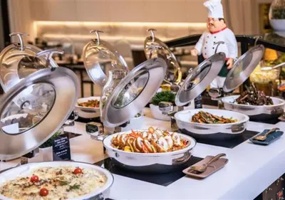 a buffet line with plates of food and a chef at Arjaan by Rotana - Dubai Media City in Dubai