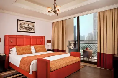 a bedroom with a red bed and a large window at Arjaan by Rotana - Dubai Media City in Dubai