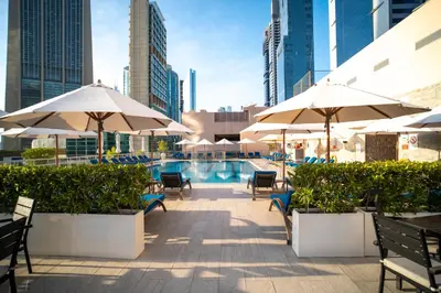 a swimming pool with umbrellas and tables and chairs and a pool at Rose Rayhaan by Rotana - Dubai in Dubai