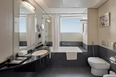 a bathroom with a sink and a tub and a toilet at Rose Rayhaan by Rotana - Dubai in Dubai