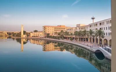 a river in a city with buildings and a bridge at Millennium Lakeview Residences in Dubai