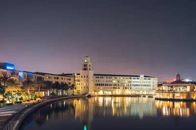 a large building next to a body of water at night at Millennium Lakeview Residences in Dubai