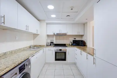 a large white kitchen with white cabinets and appliances at Millennium Lakeview Residences in Dubai
