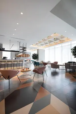 a lobby with chairs and tables and a kitchen at Ecos Dubai Hotel at Al Furjan in Dubai