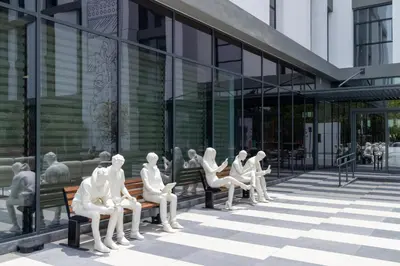 a group of mannequins sitting on benches outside a building at Ecos Dubai Hotel at Al Furjan in Dubai