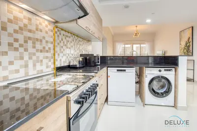a kitchen with a washing machine and a washer and dryer at Sunny 1BR at Canal Residences West Dubai Sports City by Deluxe Holiday Homes in Dubai