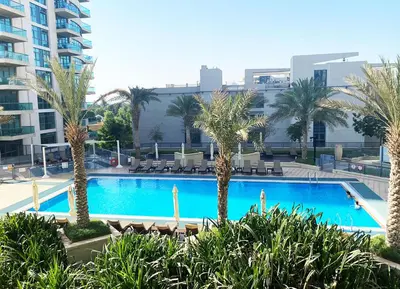 a large swimming pool with palm trees in a city at RH - Beautiful canal view, Sleek & spacious Studio, central location in Dubai