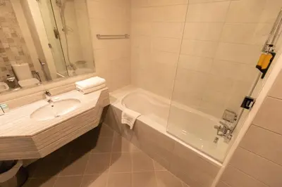a white bathroom with a tub and a sink at Grand Stay Holiday Homes Rental in Dubai