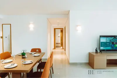 a dining room with a table and chairs and a television at HE Hotel Apartments in Dubai